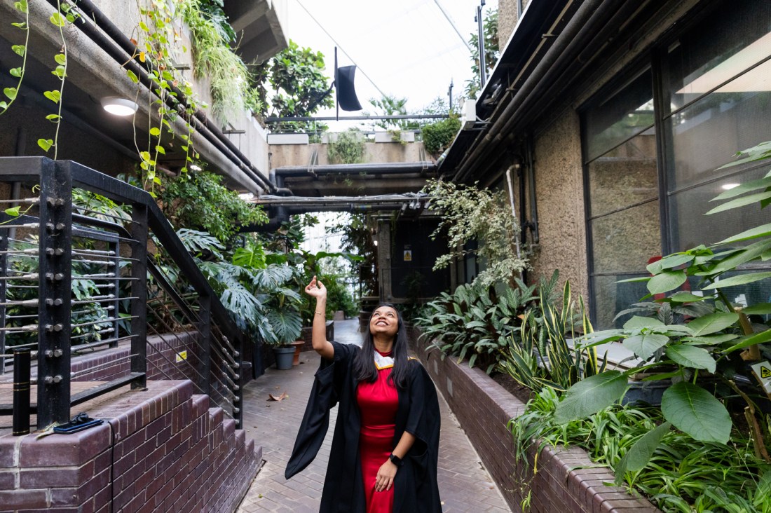 A graduate throwing their cap up in the air in a greenhouse.