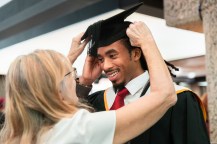 A person helps a graduate adjust their cap.