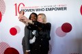 Two people taking a selfie in front of a Women Who Empower backdrop.