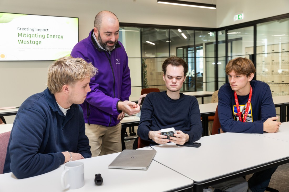 Three students looking at an AI powered plug socker.