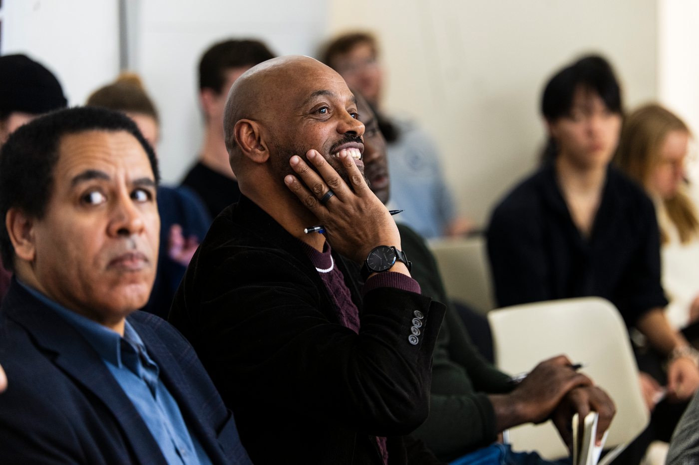 A church member smiling while listening to students present architectural designs.