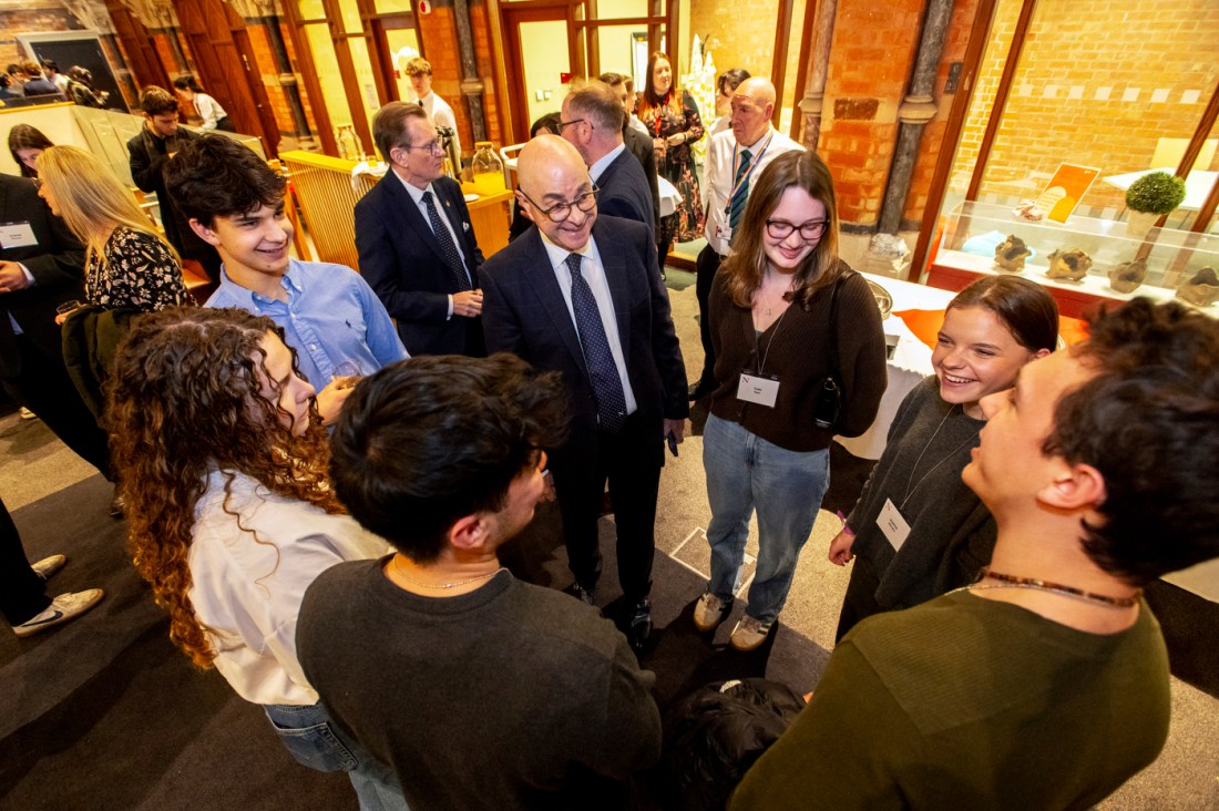 Joseph E. Aoun, Northeastern University President, smiling and engaging in conversation with a group of students during Thanksgiving dinner.