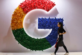 A person walking past a Google logo on a wall.