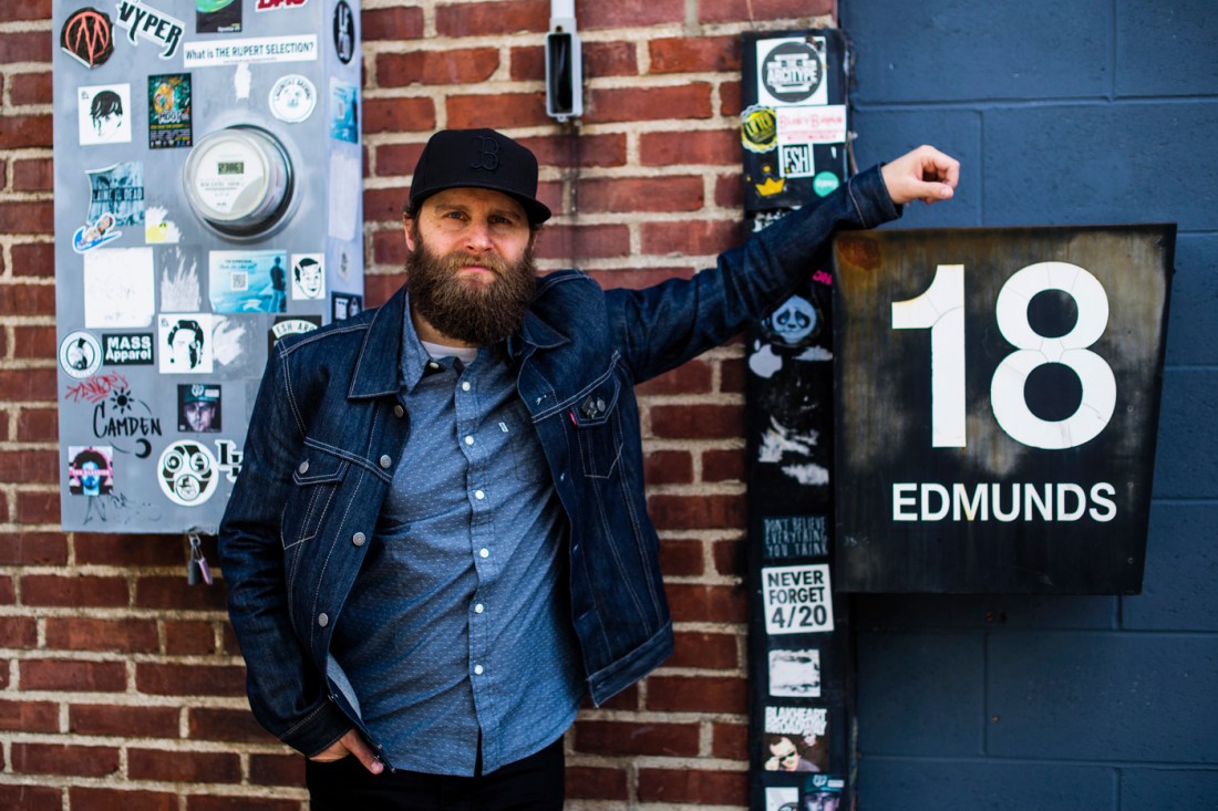 Jonathan Ulman posing in front of a brick wall. 