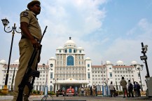 Police standing guard outside of a large white building in India.