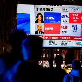 The silhouette of a person watching a large screen TV showing the election coverage.