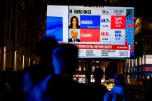 The silhouette of a person watching a large screen TV showing the election coverage.