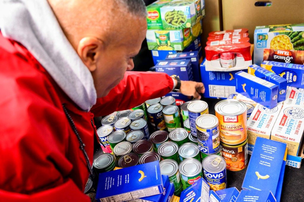 A person placing a toy on a table full of toys for a toy drive.