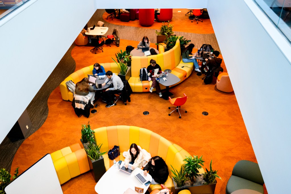 Students studying on orange chairs in Snell Library.