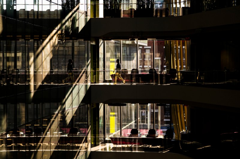 Framed by light and shadow, a student walks through the Interdisciplinary Science and Engineering Complex on Northeastern's Boston campus.