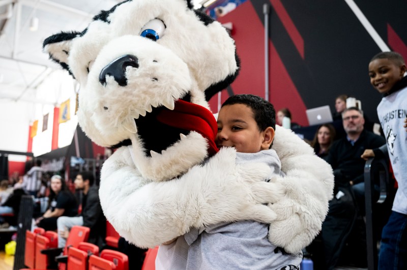 The Paws mascot hugging a student.