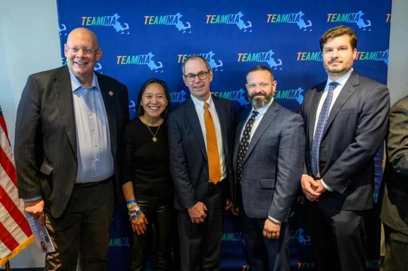 Five people posing in front of a 'TeamMA' background.