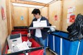 A student placing donations in a bin in a storage pod.