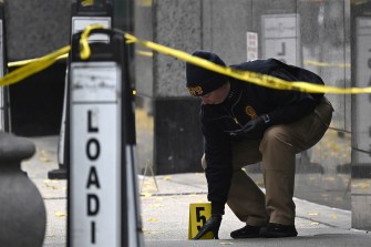 A police officer on the scene of a crime behind yellow caution tape.