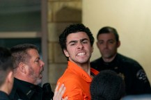 Luigi Mangione wearing an orange jumpsuit while being taken into a courthouse.