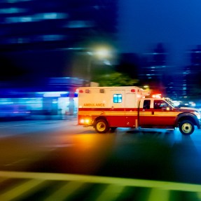 A time lapse photo of an ambulance speeding across an intersection.