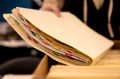 A person placing a manilla folder full of papers on a table.