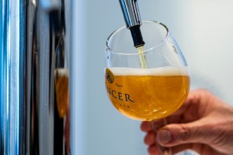 A person filling a glass of beer at a brewery.