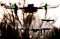 Silhouettes of drones flying in an outdoor setting.