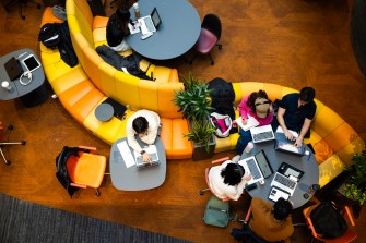 People study on a colorful couch that is the shape of an "S."