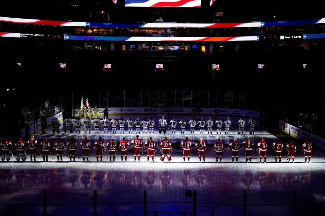 Northeastern and BU hockey players lined up facing each other on the ice.