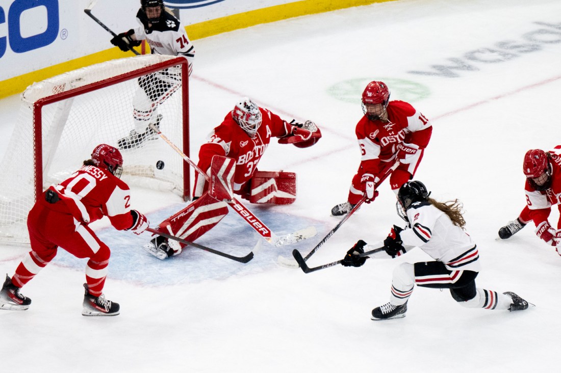 A Northeastern womens hockey player scoring a goal on BU.