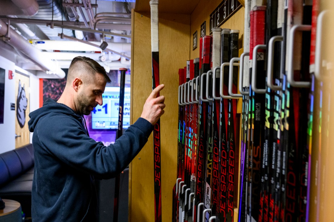 Dana Gobeil organizing a rack of hockey sticks. 