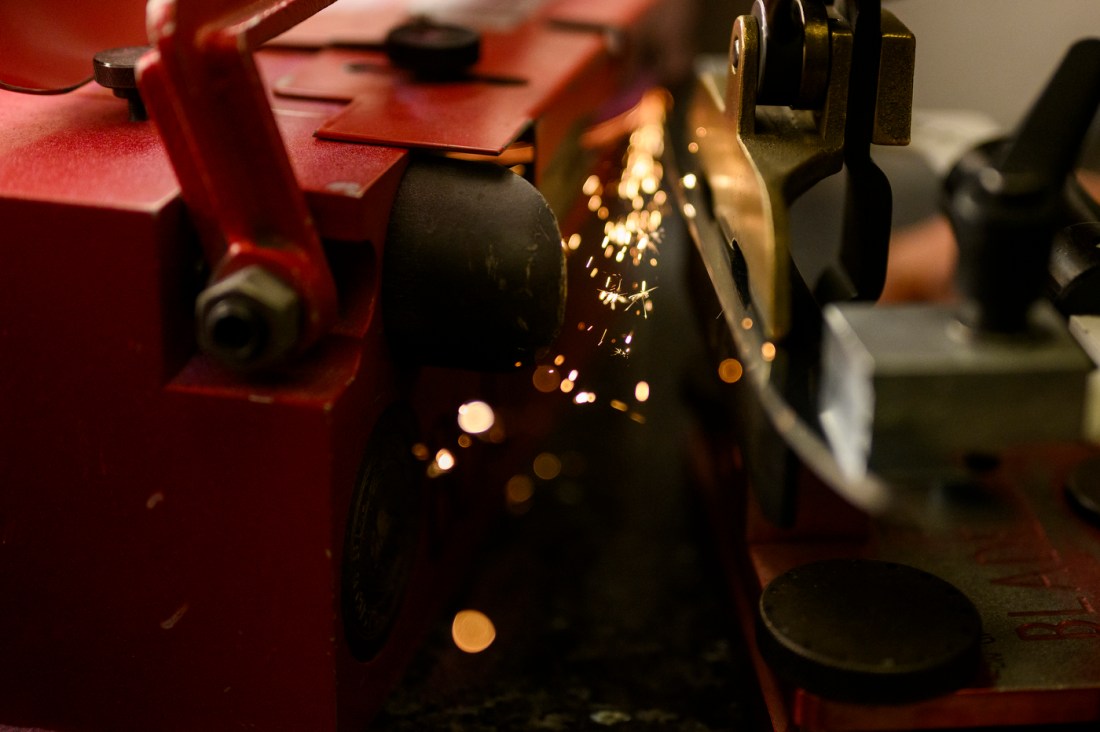 A hockey sharpening tool sending sparks off of a blade.