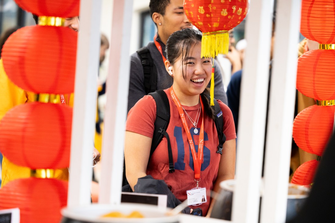 A student standing in front of red Chinese paper lanterns laughing.