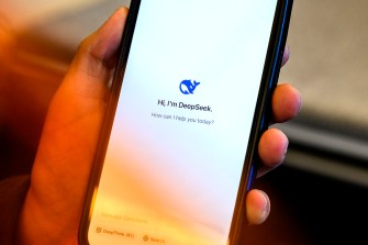 A hand holding an iphone open to the DeepSeek platform.