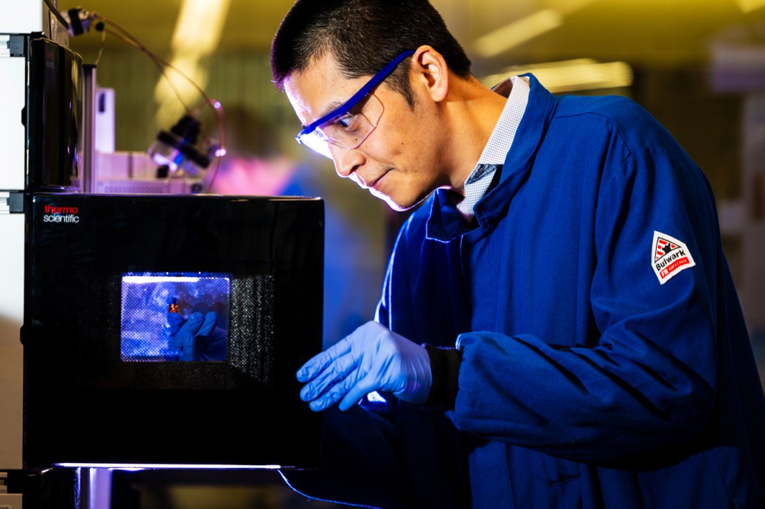 Jing Ke-Weng looking intently at a vial in the lab.