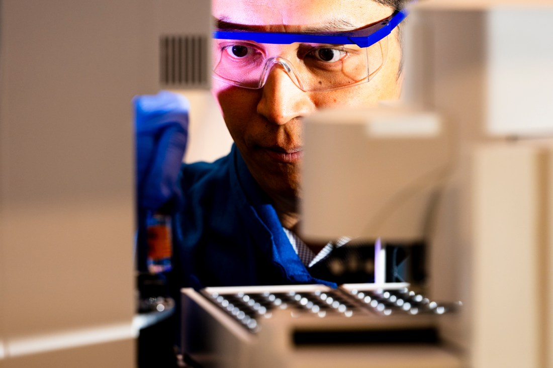 Jing-Ke Weng, Northeastern professor of chemistry, stands in his lab, surrounded by scientific equipment and a focused expression.