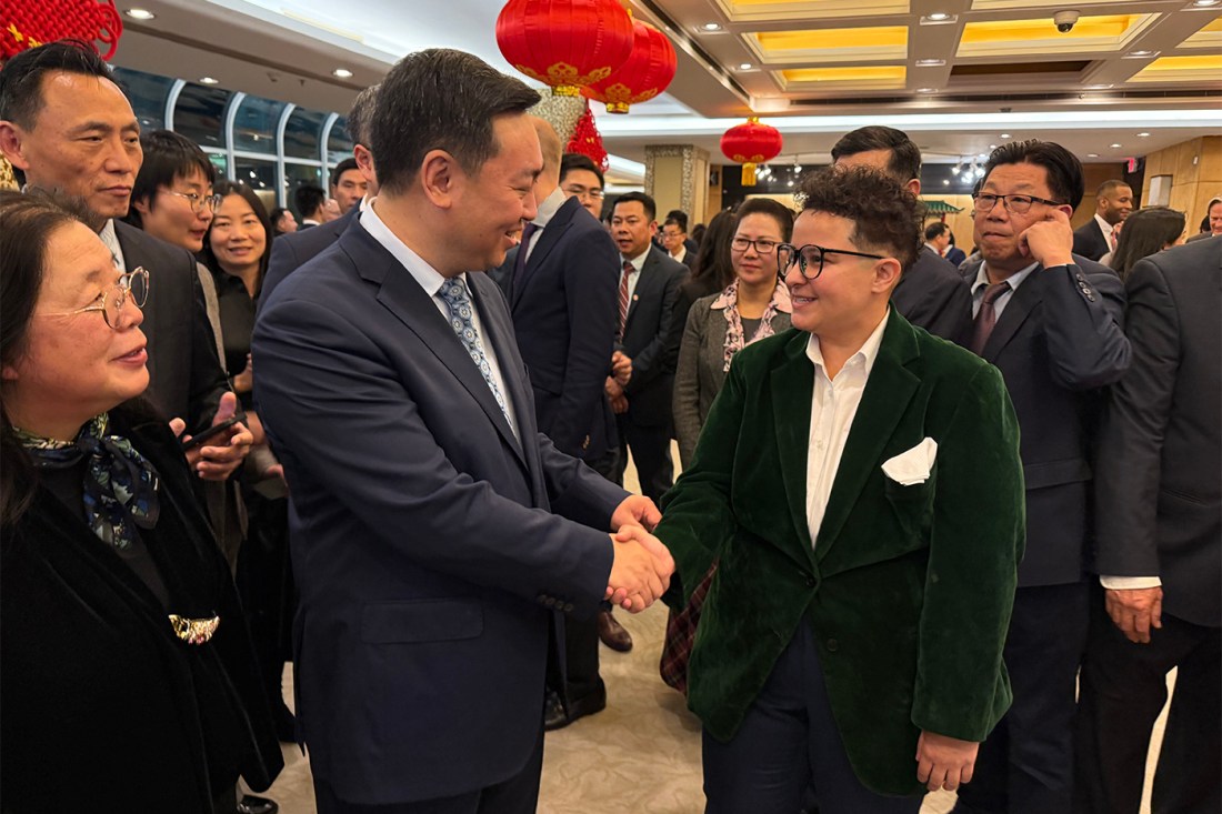 Gabby Gabriel standing amongst a crowd of people shaking hands with Ambassador Chen, of the Consulate General of the People's Republic of China.