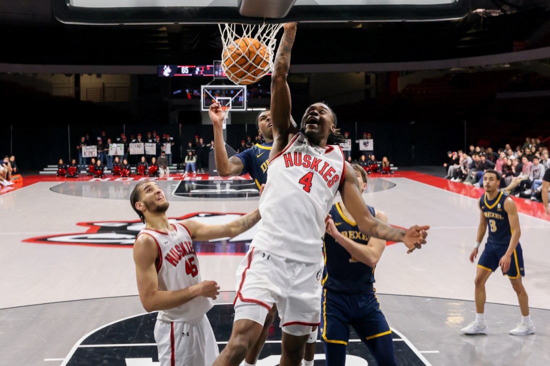 A Northeastern mens basketball player dunking the ball into the net.