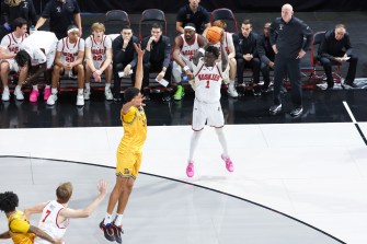 A Northeastern mens basketball player holding the ball above his head.