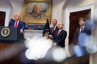 Donald Trump and several other men standing in a room at the white house. Donald Trump is standing behind a podium with a microphone.