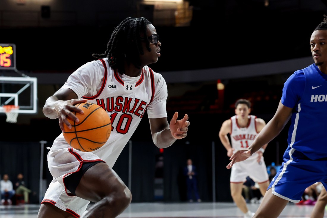 A Northeastern mens basketball player dribbling with the ball.