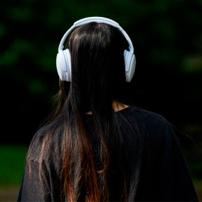 A person wearing over the ear headphones photographed from behind.