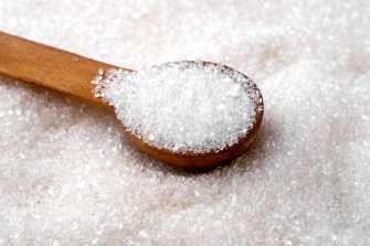 A wooden spoon filled with sugar in a pile of sugar.