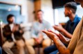 A close up of a person applauding while sitting in a circle with a support group.