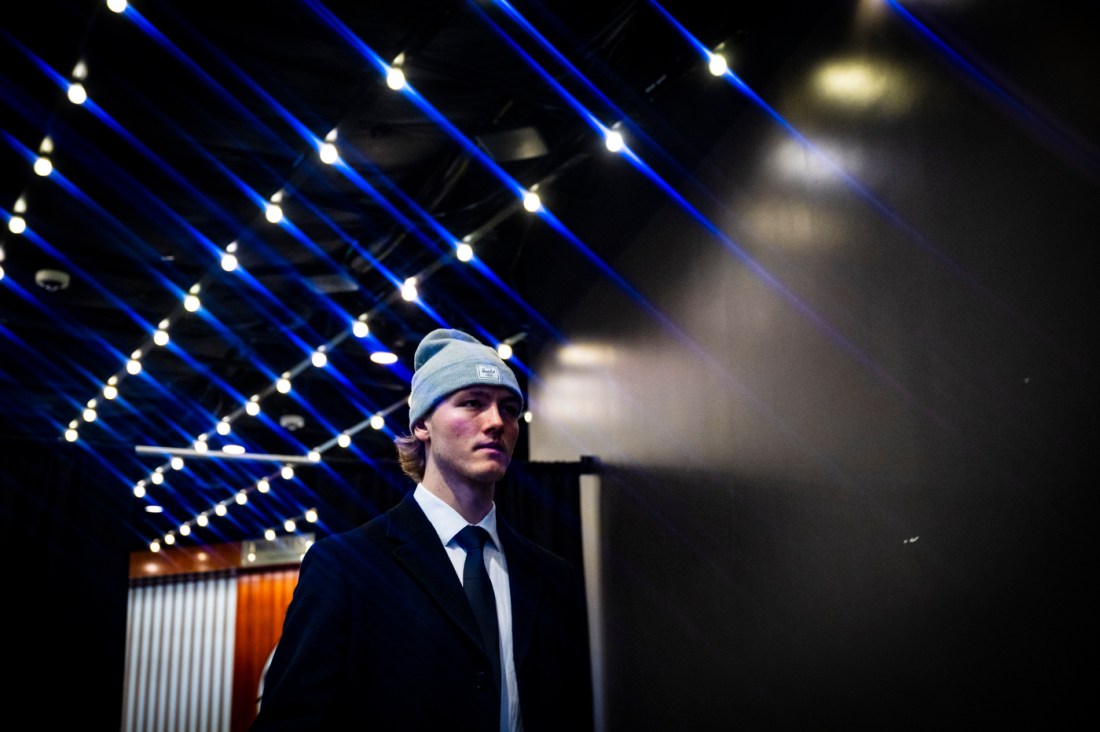 A mens hockey player wearing a suit, tie and grey beanie walking into TD Garden.