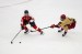 A Northeastern hockey player skates on the ice with the puck while a BC hockey player sticks his hockey stick in the players path.