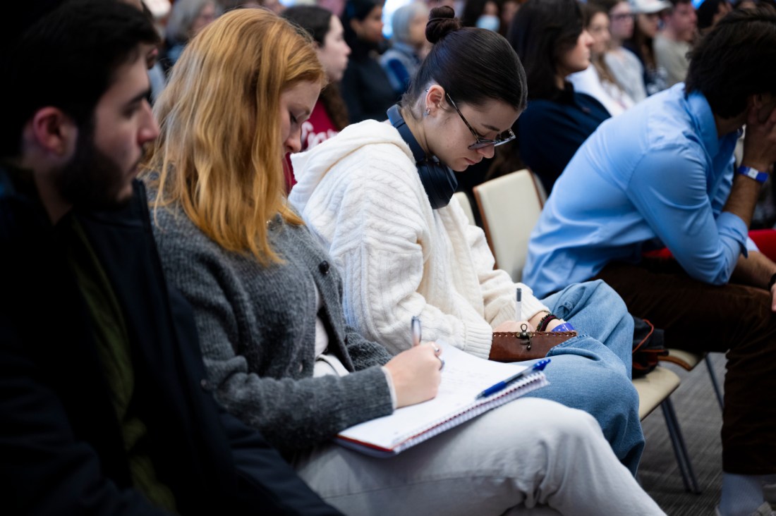 An audience member taking notes in a notebok at the fireside chat.