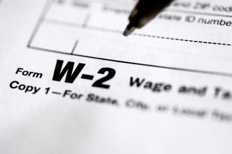 A pen hovering above a tax form that says 'form W-2 copy 1' on it.