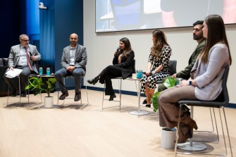 Six people sitting on a stage in chairs.