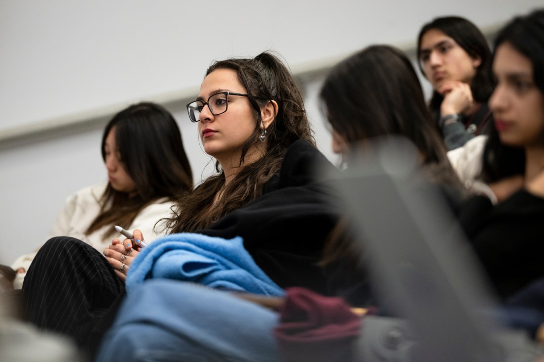 An audience member wearing glasses listening to a panel discussion. 