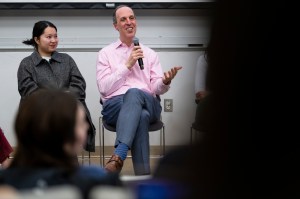 Mike Armini sitting at the front of a classroom speaking into a microphone.