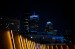 A city skyline at night with illuminated buildings and lights in the foreground.