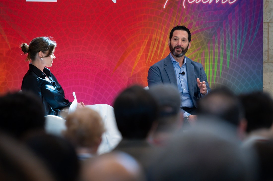 Two speakers wearing microphones sitting on stage at the Global Leadership Summit in Miami.