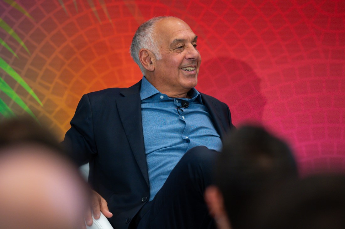 A person wearing a blue shirt and black blazer sitting on stage at the Global Leadership Summit in Miami.